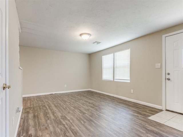 empty room with visible vents, baseboards, and wood finished floors