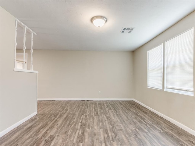 empty room with visible vents, baseboards, and wood finished floors