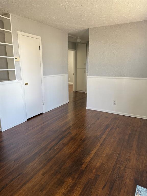 spare room featuring a textured wall, dark wood finished floors, and a textured ceiling