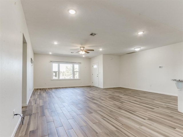 spare room with light wood-type flooring, visible vents, ceiling fan, and baseboards