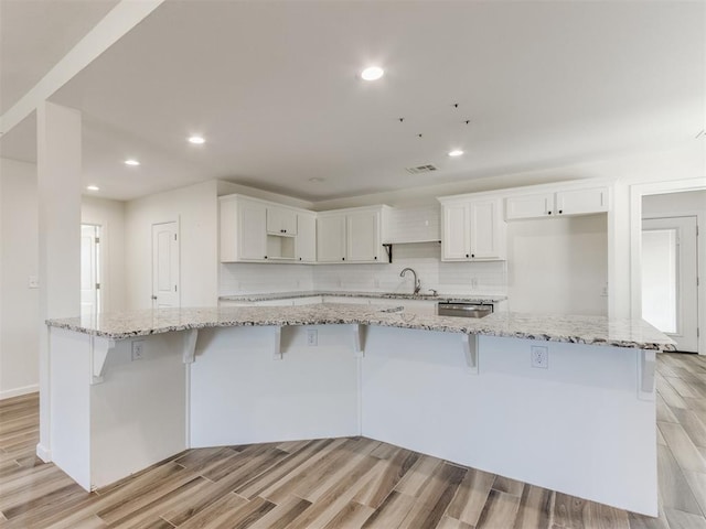 kitchen featuring wood tiled floor, white cabinetry, decorative backsplash, and recessed lighting