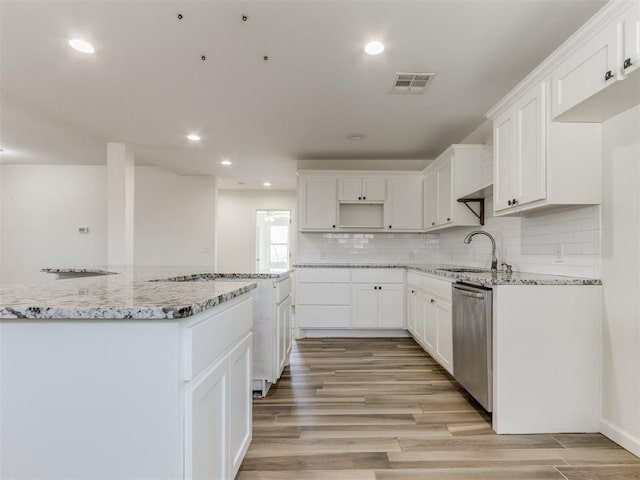 kitchen featuring light stone counters, visible vents, stainless steel dishwasher, light wood-type flooring, and decorative backsplash