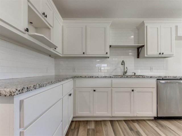 kitchen with light stone counters, stainless steel dishwasher, light wood-style floors, white cabinets, and a sink