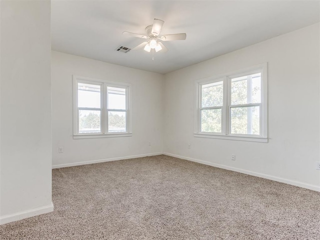 empty room featuring a ceiling fan, carpet, visible vents, and baseboards