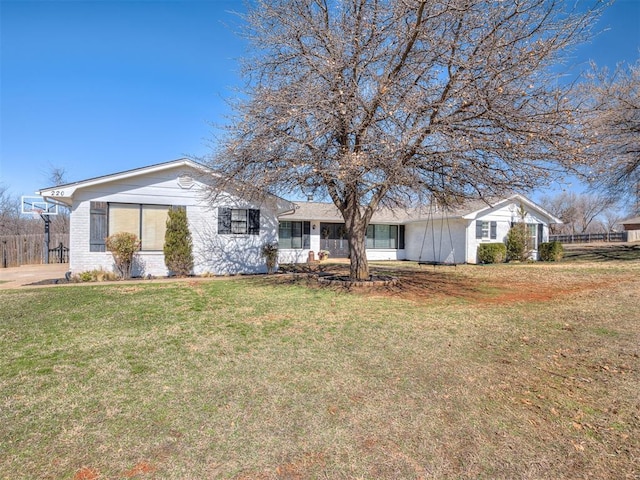 single story home featuring a front lawn, fence, and brick siding