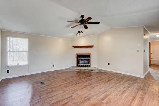 unfurnished living room with lofted ceiling, a ceiling fan, wood finished floors, a glass covered fireplace, and baseboards