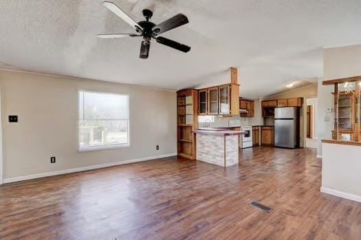 unfurnished living room with visible vents, lofted ceiling, a textured ceiling, a ceiling fan, and dark wood-style flooring