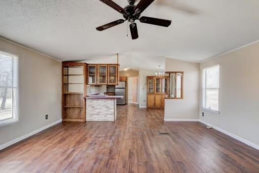 unfurnished living room with dark wood finished floors, vaulted ceiling, baseboards, and a textured ceiling