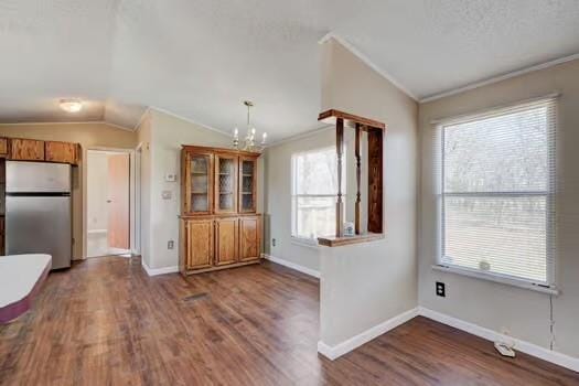 kitchen with brown cabinetry, dark wood finished floors, lofted ceiling, freestanding refrigerator, and ornamental molding