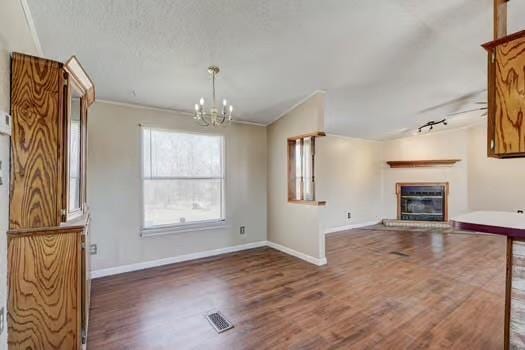 unfurnished living room with a glass covered fireplace, visible vents, baseboards, and wood finished floors