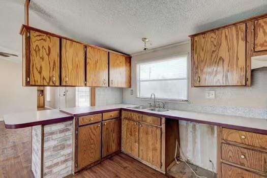 kitchen featuring light countertops, wood finished floors, brown cabinets, and a sink