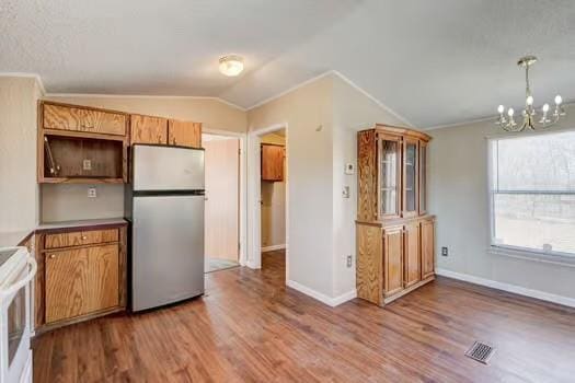 kitchen featuring wood finished floors, visible vents, freestanding refrigerator, vaulted ceiling, and range