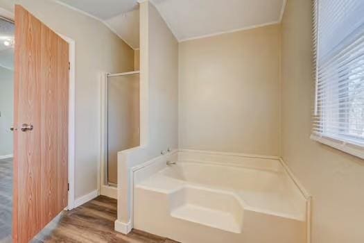 full bath with a bath, wood finished floors, and a stall shower