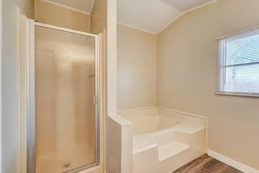 full bathroom with baseboards, lofted ceiling, a garden tub, and a shower stall