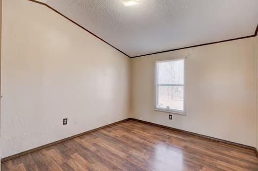 unfurnished room with vaulted ceiling, ornamental molding, a textured ceiling, and wood finished floors