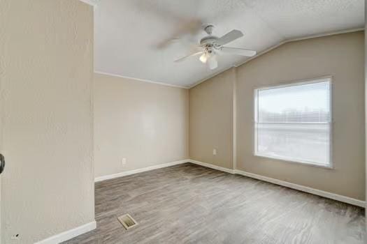 spare room with a ceiling fan, wood finished floors, baseboards, lofted ceiling, and a textured ceiling