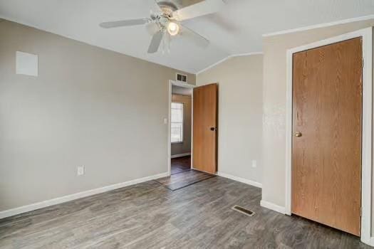 unfurnished bedroom with visible vents, baseboards, wood finished floors, and vaulted ceiling