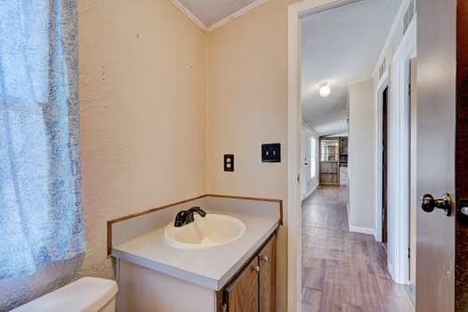 bathroom with vanity, toilet, wood finished floors, and ornamental molding