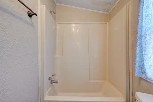 full bath with shower / bath combination, ornamental molding, and a textured wall