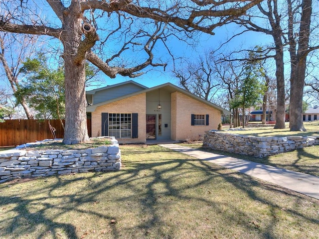 view of side of property featuring a yard, brick siding, and fence