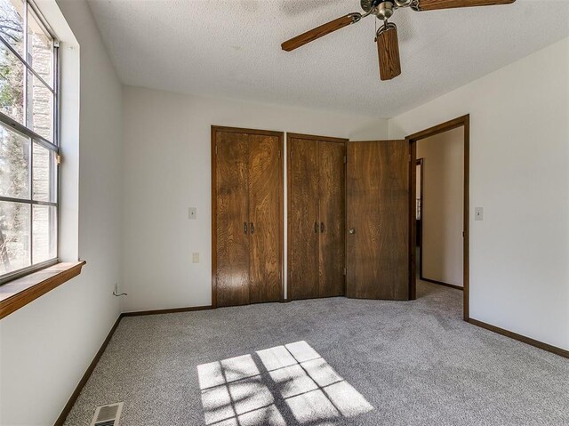 2000 N Alexander Ln, Bethany, OK 73008 - unfurnished bedroom with multiple windows, carpet floors, a textured ceiling, and a ceiling fan