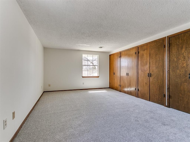 2000 N Alexander Ln, Bethany, OK 73008 - unfurnished bedroom featuring light carpet, a textured ceiling, and two closets