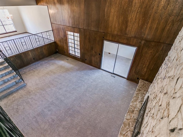 2000 N Alexander Ln, Bethany, OK 73008 - unfurnished living room with wooden walls, carpet flooring, healthy amount of natural light, and a chandelier