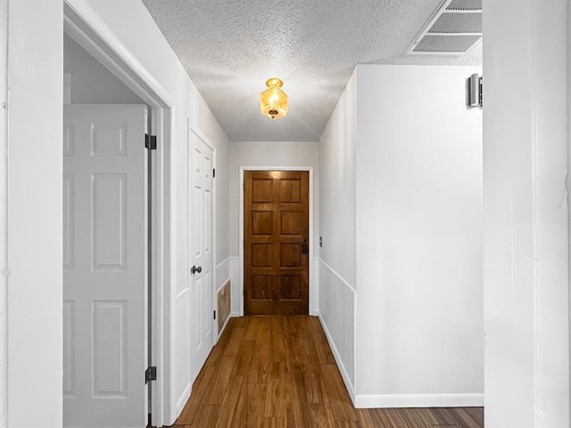 entryway with a textured ceiling, visible vents, and wood finished floors