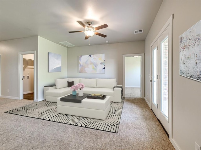 carpeted living area with a ceiling fan, visible vents, plenty of natural light, and baseboards