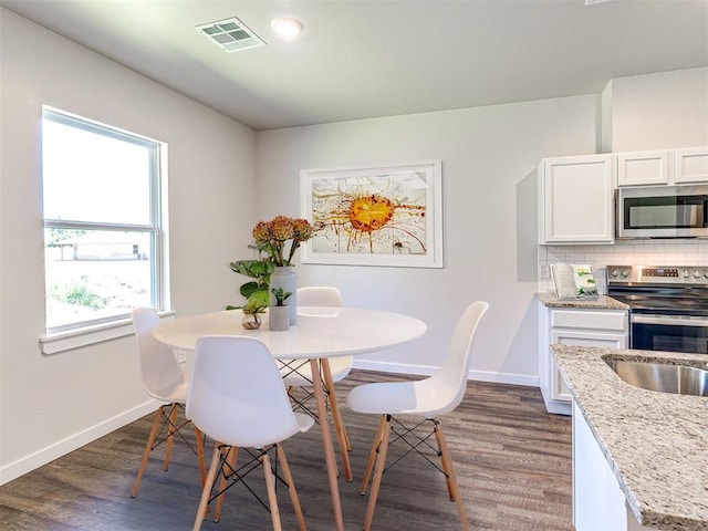 dining room with baseboards, visible vents, and dark wood-style flooring