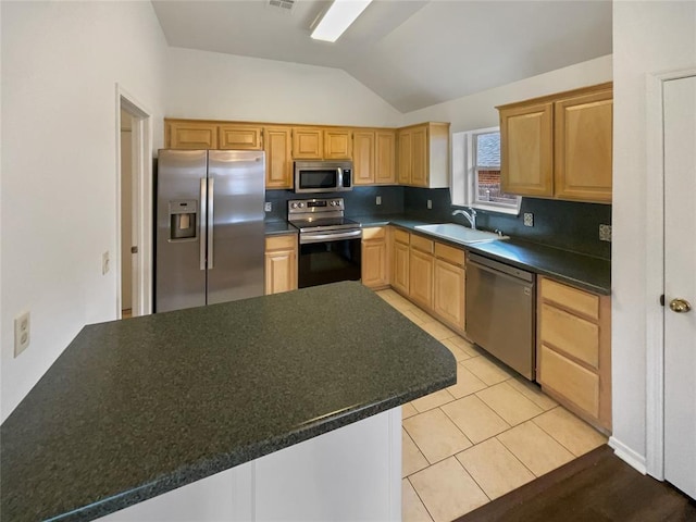 kitchen featuring light tile patterned flooring, a sink, vaulted ceiling, appliances with stainless steel finishes, and dark countertops