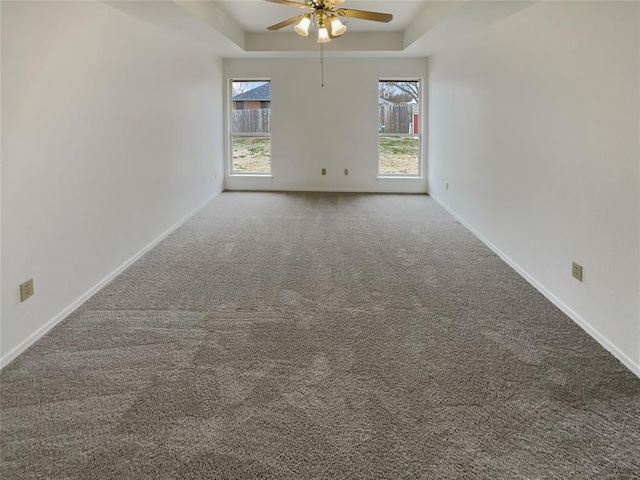 spare room featuring a ceiling fan, a raised ceiling, baseboards, and carpet floors