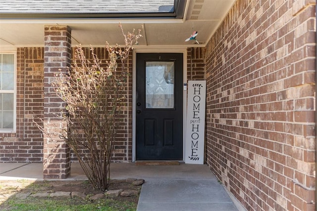 entrance to property with brick siding and roof with shingles