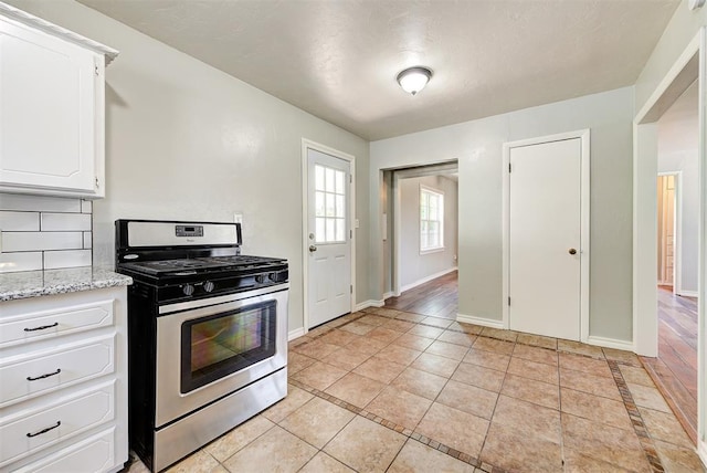 2625 SW 46th St, Oklahoma City, OK 73119 - kitchen with stainless steel gas range oven, light tile patterned floors, baseboards, and white cabinets