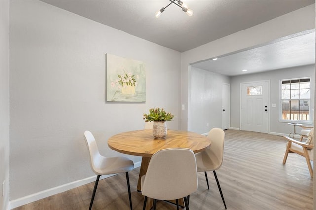 dining room with baseboards, light wood-style floors, and a textured ceiling