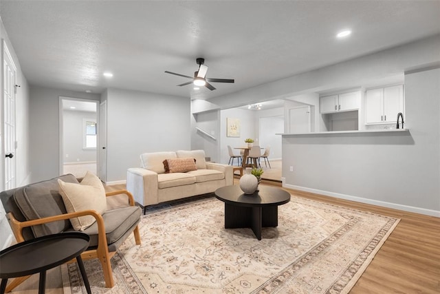 living area featuring recessed lighting, light wood-type flooring, baseboards, and a ceiling fan