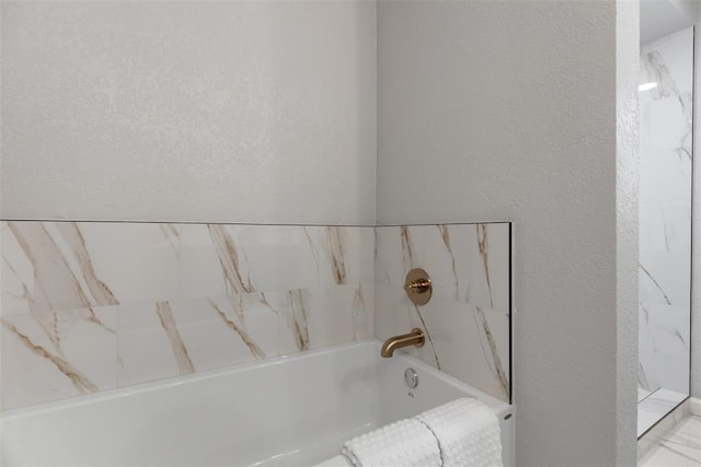 bathroom featuring a bathing tub and a textured wall