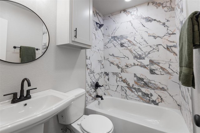 bathroom featuring a sink, toilet, bathing tub / shower combination, and a textured wall