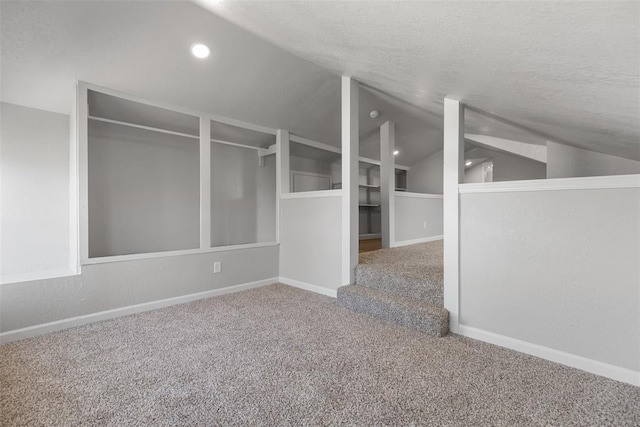 carpeted spare room with lofted ceiling, baseboards, and a textured ceiling