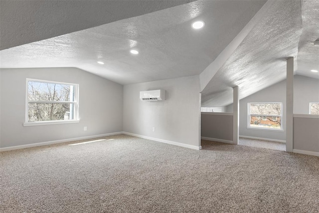 bonus room featuring a wall unit AC, carpet flooring, baseboards, and vaulted ceiling