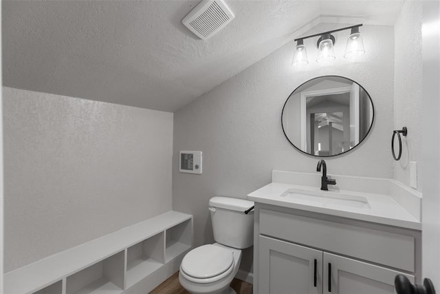 bathroom with visible vents, toilet, vaulted ceiling, a textured wall, and a textured ceiling