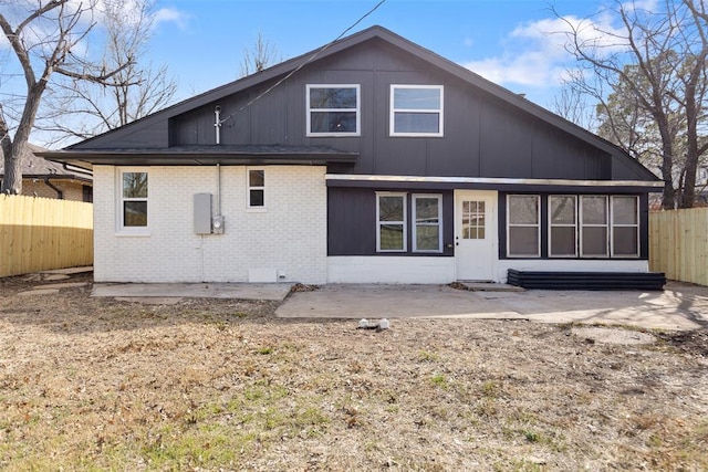 rear view of house with brick siding, a patio, and fence