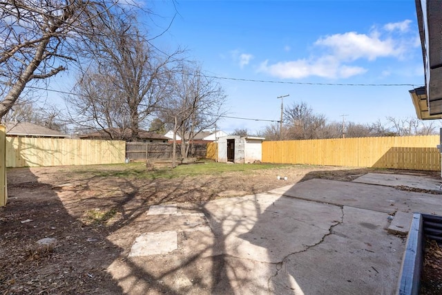 view of yard featuring a storage shed, an outbuilding, a fenced backyard, and a patio