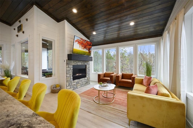 sunroom with a stone fireplace, wood ceiling, and vaulted ceiling