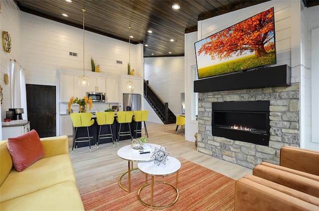 living room featuring stairs, visible vents, wood ceiling, and light wood-type flooring