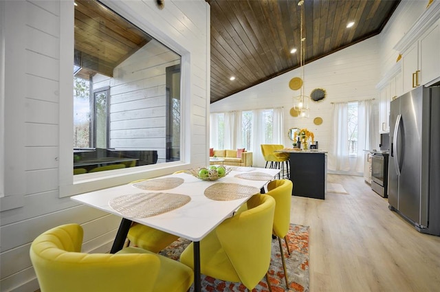 dining room featuring light wood finished floors, wood walls, wood ceiling, and a wealth of natural light