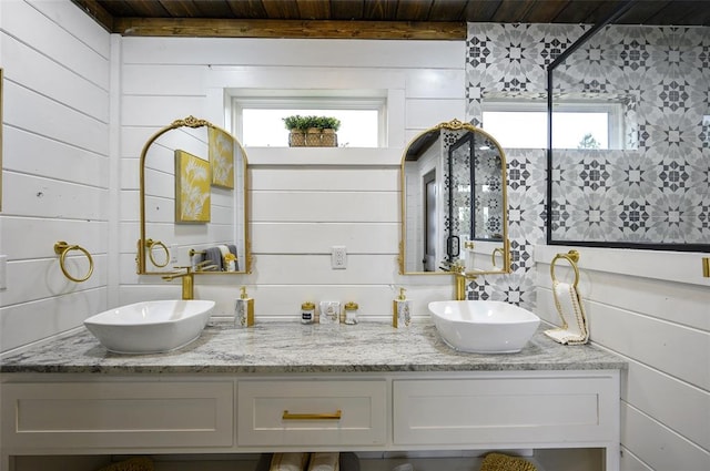 bathroom with double vanity, wooden walls, and a sink