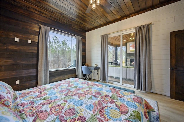 bedroom featuring wood finished floors, a fireplace, wood walls, wooden ceiling, and access to outside