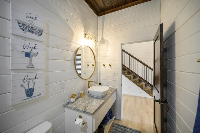 bathroom with wood walls, toilet, wooden ceiling, wood finished floors, and vanity