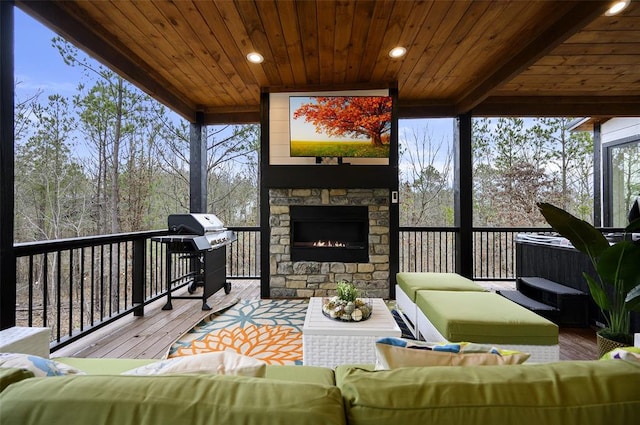 sunroom / solarium featuring plenty of natural light, wood ceiling, and an outdoor stone fireplace